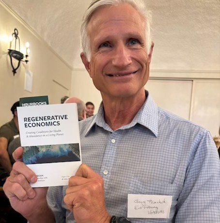 Gary Tomchuk holding a book on Regenerative Economics